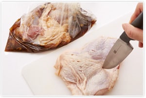 鳥もも肉をまな板に乗せ、味がしみ込みやすいよう、包丁やフォークで皮のほうに穴をあける。1の下味調味料入りのビニール袋に入れて30分漬け込む。