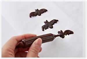 チョコペンでコウモリを作る、少し厚みを出してコウモリの形に絞り出して、しっかり冷やす。はがして裏のツルッとした方を表にして使う。その他お好みの飾りをつけて完成。